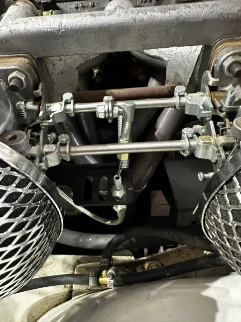 Twin carburettor throttle linkage and fuel line