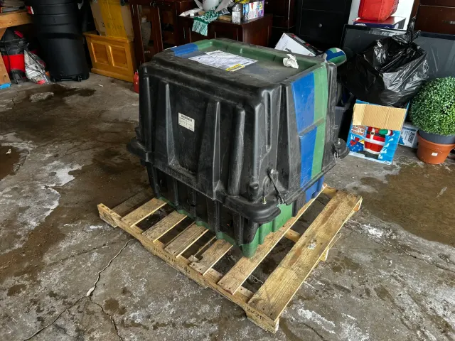Large plastic storage crate on wooden pallet in garage