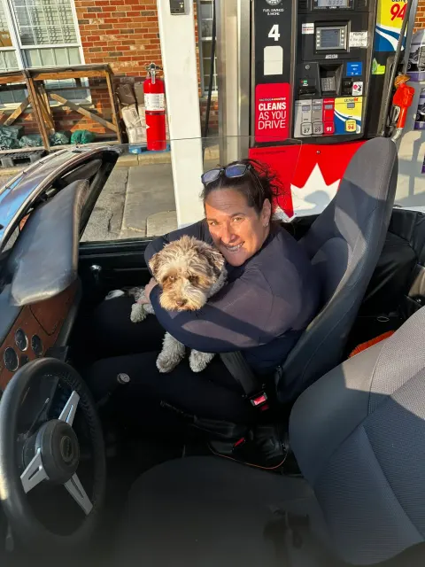 Passenger and dog in convertible at petrol station