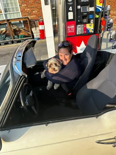 Driver and dog in open roadster at petrol station