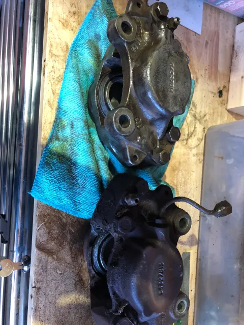 Pair of removed front brake calipers on bench