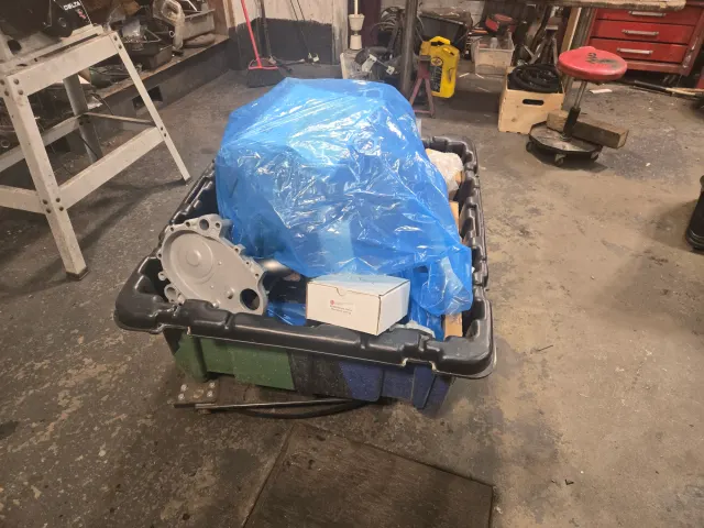 Boxed engine parts under blue plastic sheeting
