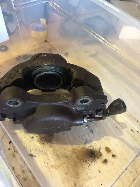 Dismantled front brake caliper half awaiting cleanup