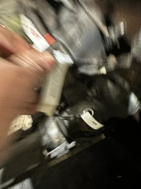 Blurred hand holding sealant tube in engine bay