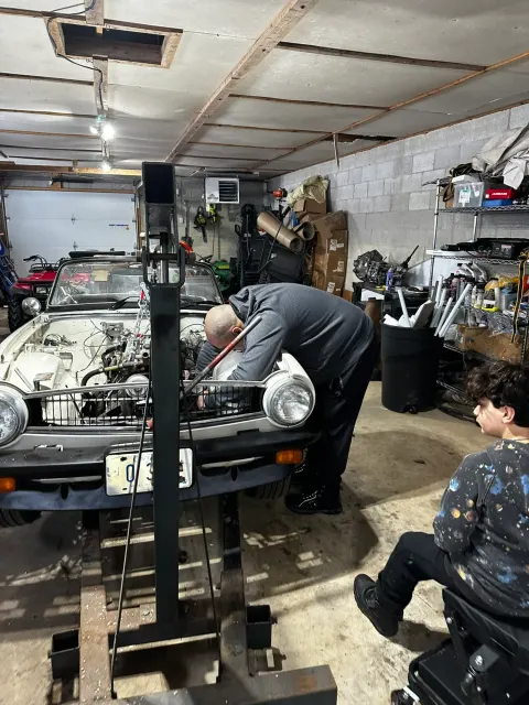 Working on classic roadster engine bay in garage