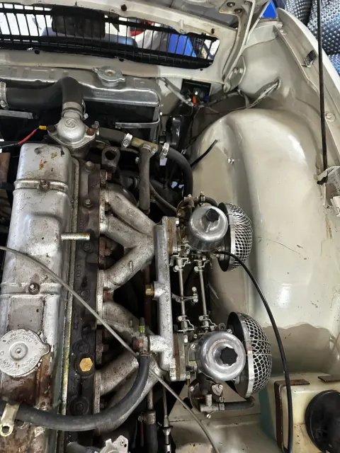 Straight-six engine bay with twin carburettors and mesh air filters