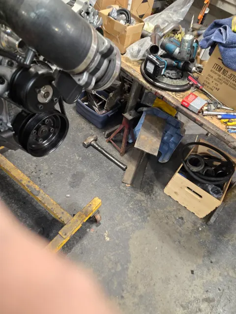 Engine on hoist beside cluttered workshop bench