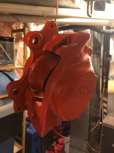 Freshly painted red brake caliper hanging to dry