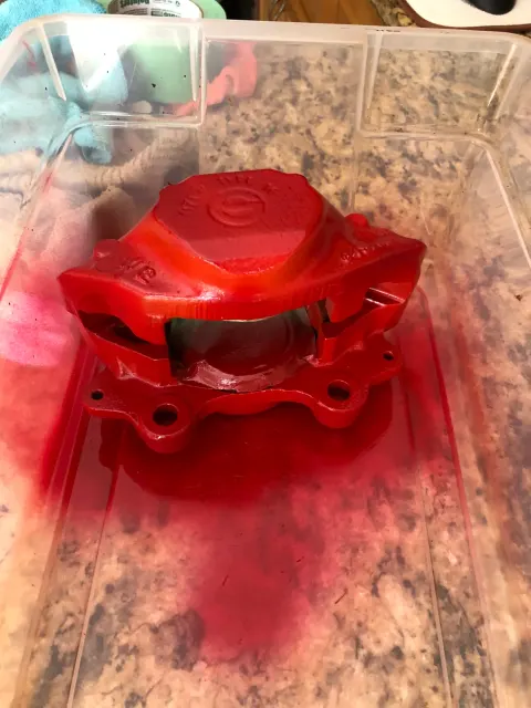 Freshly painted red brake caliper drying in tub