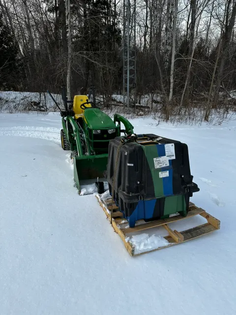 John Deere compact tractor with crated attachment in snow