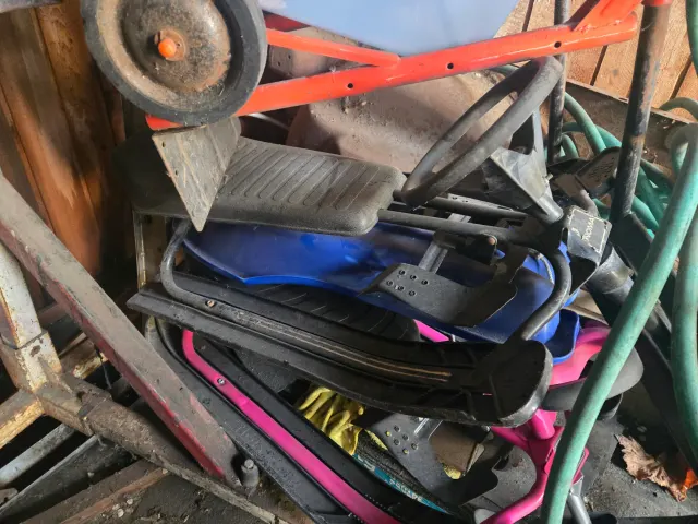 Cluttered shed corner with sledges and garden tools