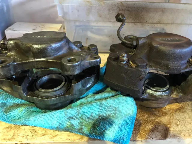 Two dismantled front brake calipers on bench